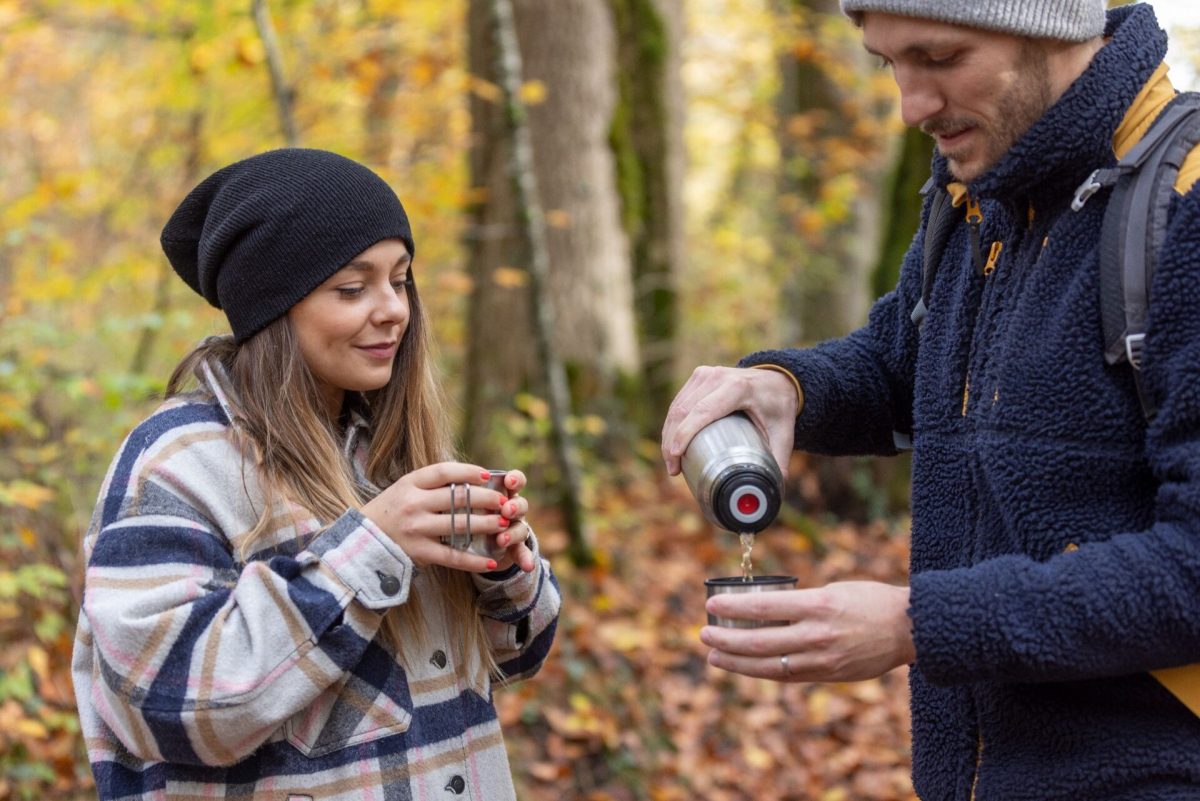 Randonneurs avec un thermos au milieu d’une forêt automnale du Haut-Giffre
